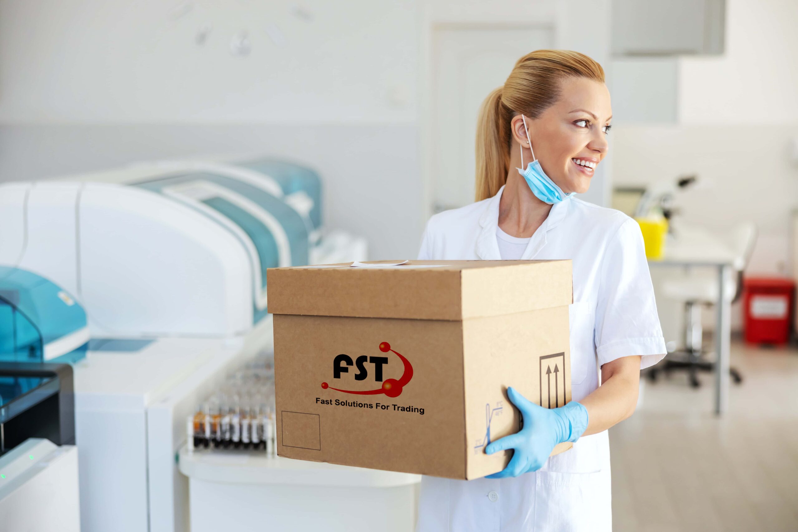 Smiling blond female lab assistant standing and holding box with